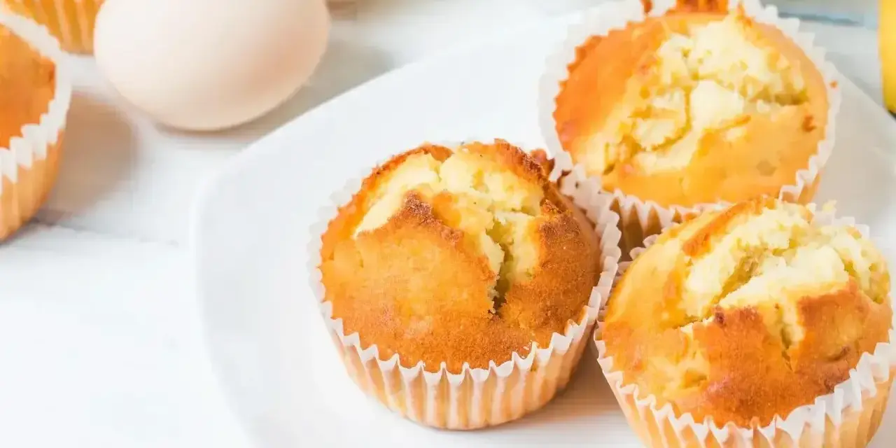 Puszyste babeczki z airfryer na białym talerzu, obok jajka. Idealne na szybkie śniadanie.