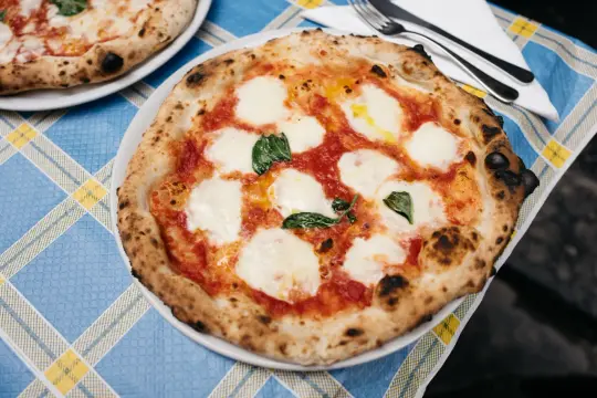 Pyszne ciasto na pizzę neapolitańską z pomidorami, mozzarellą i bazylią, gotowe do zjedzenia.