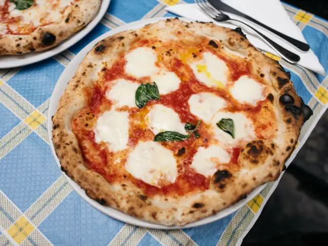 Pyszne ciasto na pizzę neapolitańską z pomidorami, mozzarellą i bazylią, gotowe do zjedzenia.