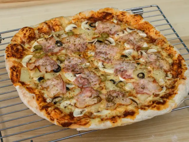 Pyszna pizza z szynką, pieczarkami i oliwkami, idealna do pieczenia w piekarniku.