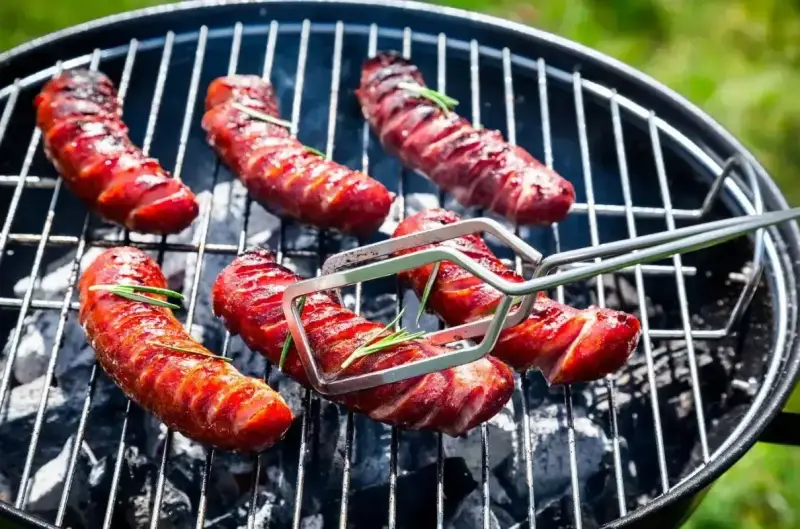 Aromatyczna kiełbasa z grilla, skwiercząca na węglu, z gałązkami rozmarynu. Idealna na letnie popołudnie.